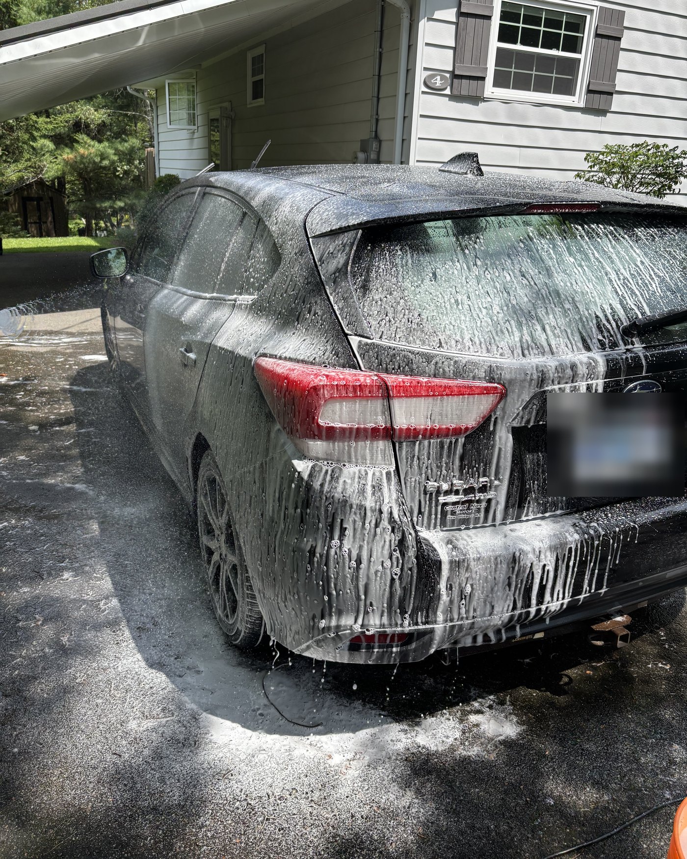 Subaru Impreza covered in foam during a mobile detail in a Truro driveway